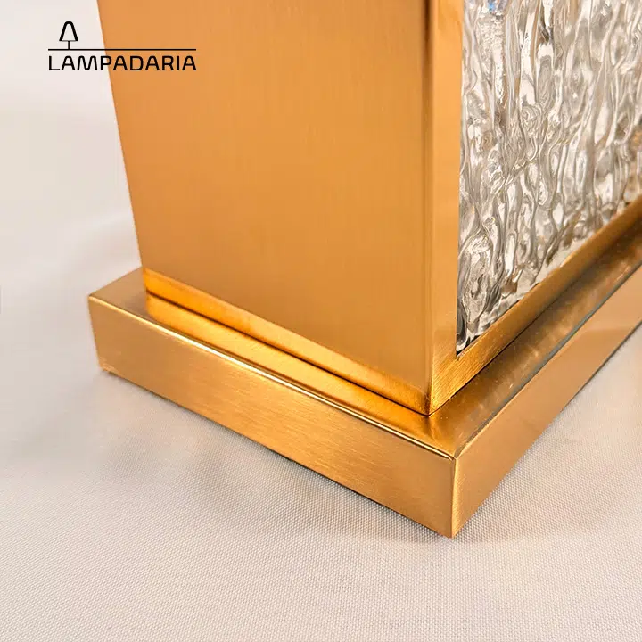 Abajur em vidro artesanal transparente e latão dourado com pantalha retangular em tecido algodão mercerizado brilhante na cor off-white.