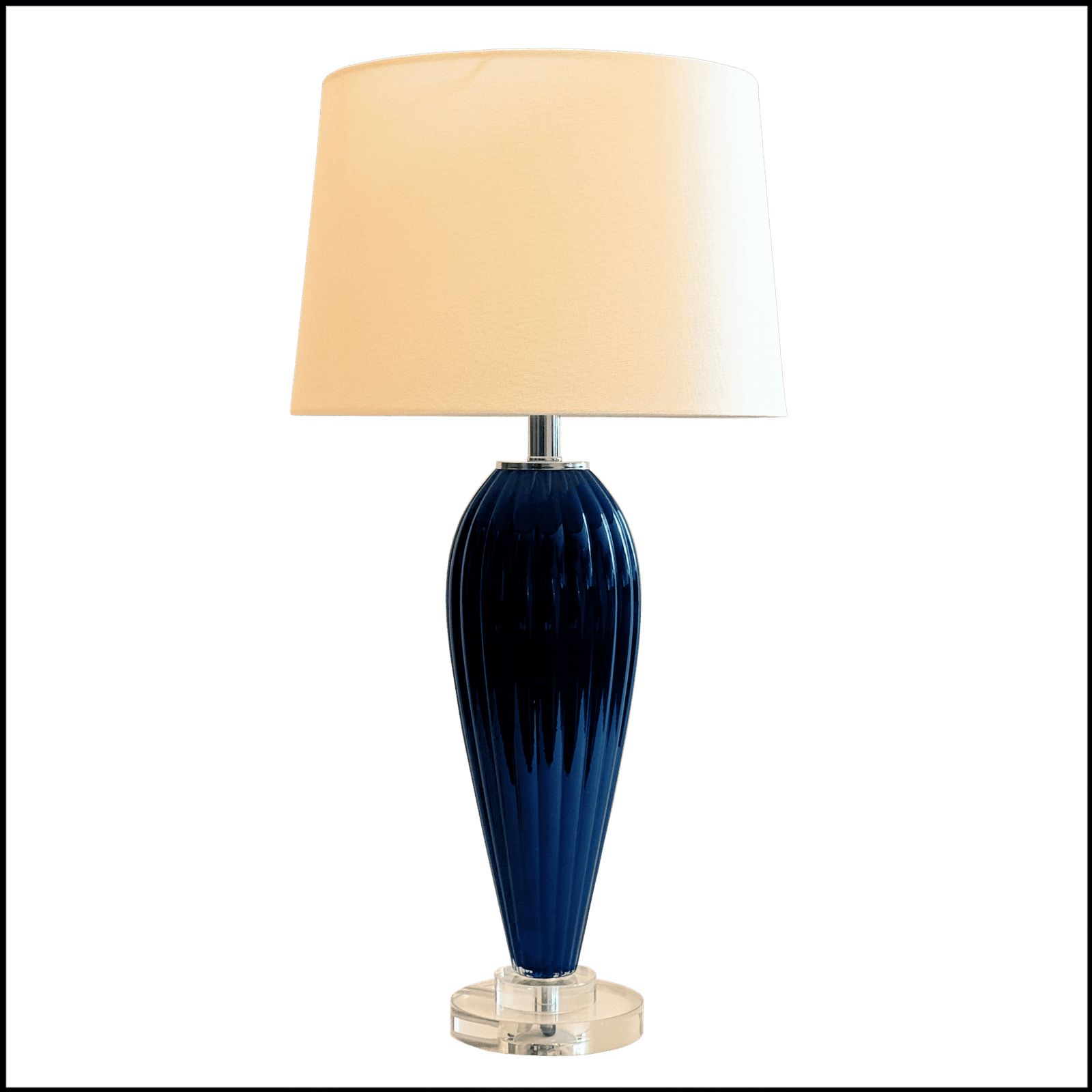 O Abajur Nightglass da Lampadaria é a perfeita fusão entre design clássico moderno, brilho e sofisticação. Sua base alta, em cristal azul noite moldada no formato de balaústre com frisos boleados e detalhes em cristal transparente, adiciona um toque de requinte e elegância ao ambiente. A cúpula translúcida em tecido algodão texturizado na cor branca distribui a luz uniformemente para cima e para baixo, criando uma atmosfera acolhedora, enquanto difunde lateralmente, contribuindo para a iluminação geral do espaço.